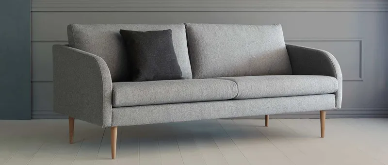 Das BERGEN Designer Sofa mit hell lackierten Eichenholzfüßen - gezeigt am 3-Sitzer Sofa